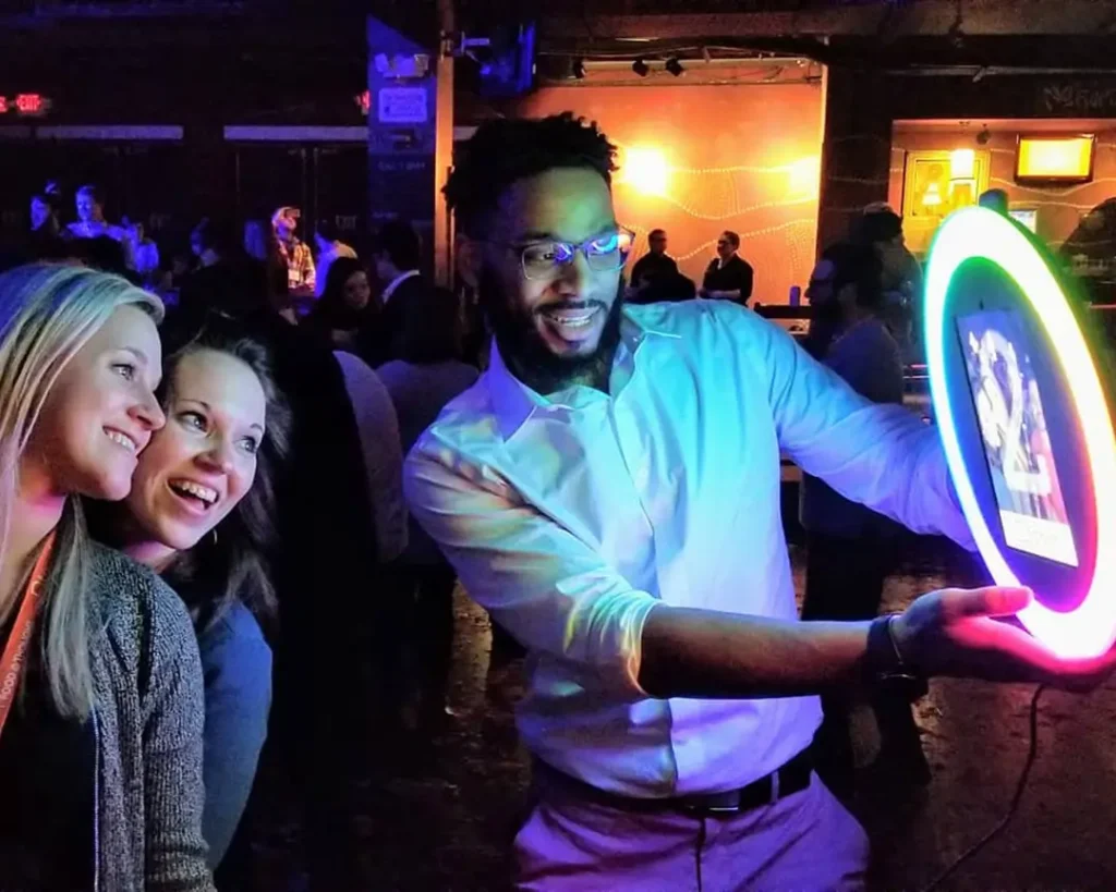 Event attendees enjoying an interactive light-up photo booth experience in a dimly lit venue setting