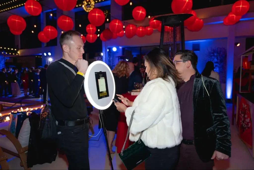 Event guests engaging with interactive digital display under festive red lanterns and blue ambient lighting