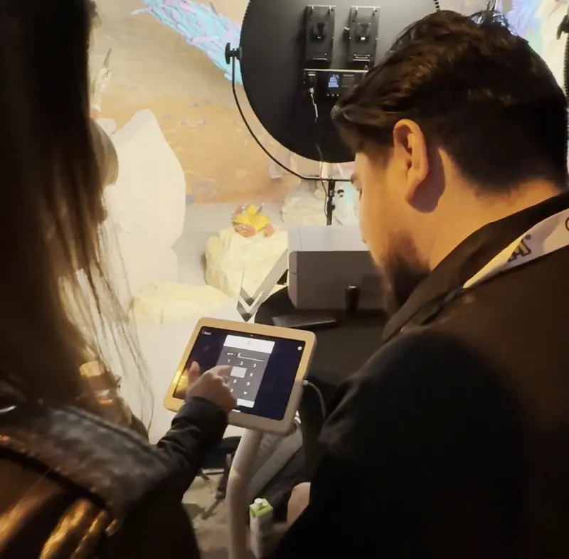 Event staff helping a guest input information on a tablet device at a photo activation station with studio lighting setup