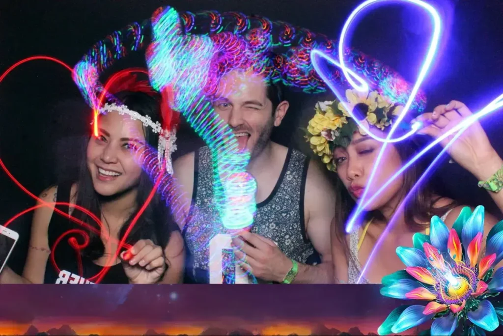 Festival attendees creating light painting art effects in an interactive photo booth with colorful LED accessories