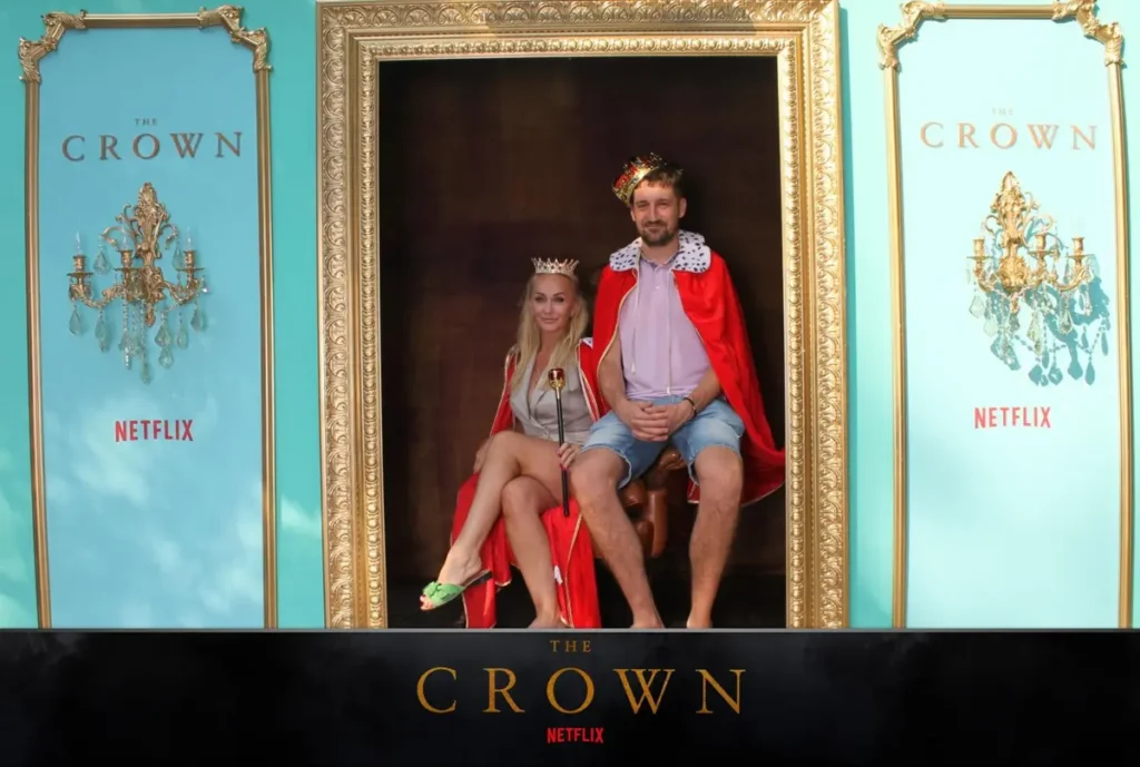 Interactive photo opportunity at a Netflix 'The Crown' promotional event with visitors posing in royal costumes on a throne