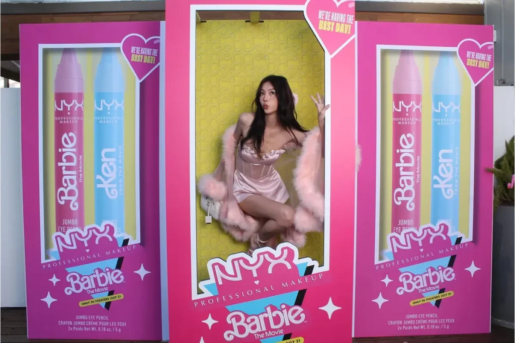 Life-sized NYX x Barbie makeup product packaging photo opportunity with woman posing inside branded display box