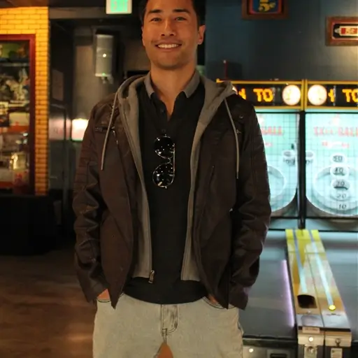 Man smiling at an event venue with arcade games in the background