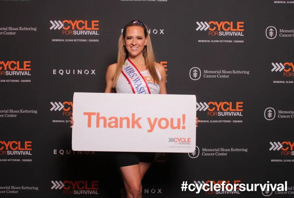 Mrs. Massachusetts holding 'Thank you!' sign at Cycle for Survival charity event photo backdrop