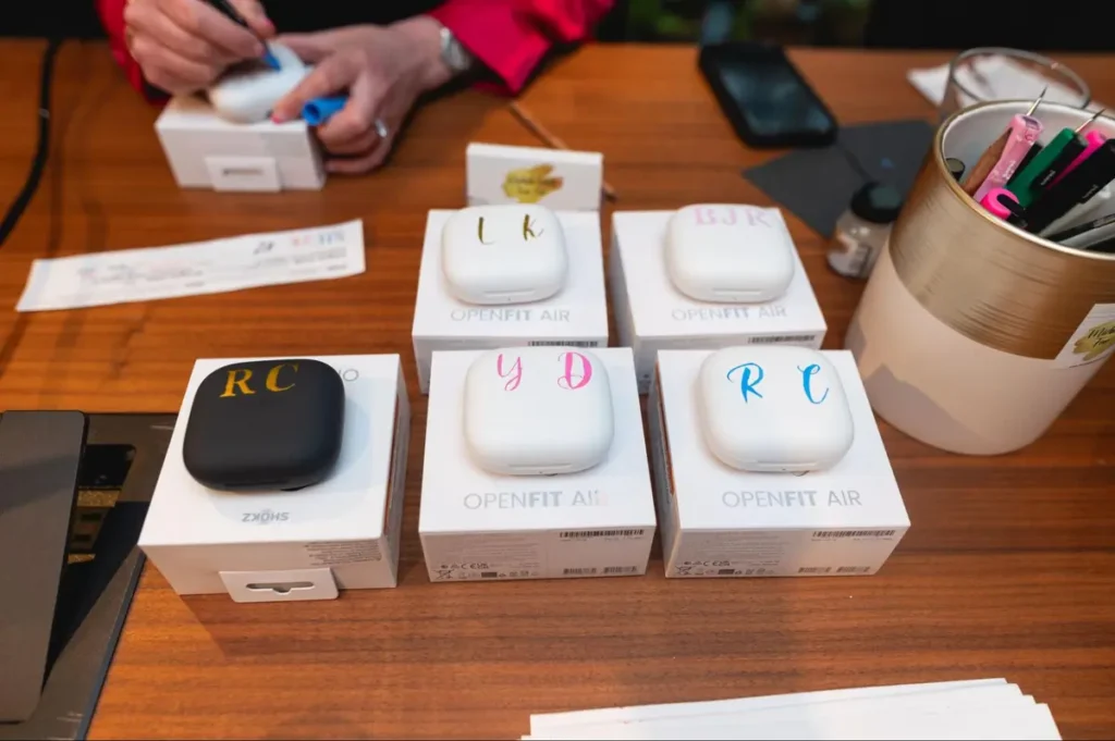 Personalized OPENFIT AIR earbuds being customized with colored monograms as unique event giveaways for attendees