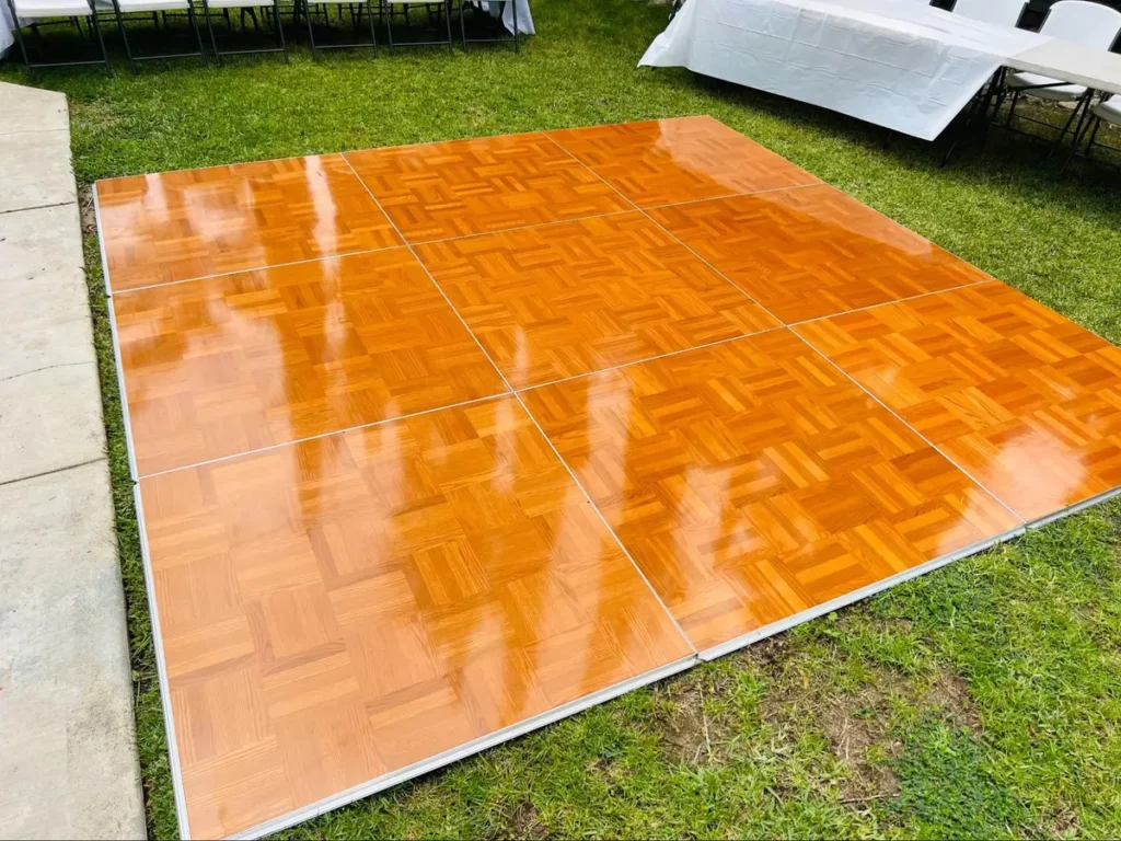 Portable wooden parquet dance floor set up outdoors on grass - modular options require advance rental planning