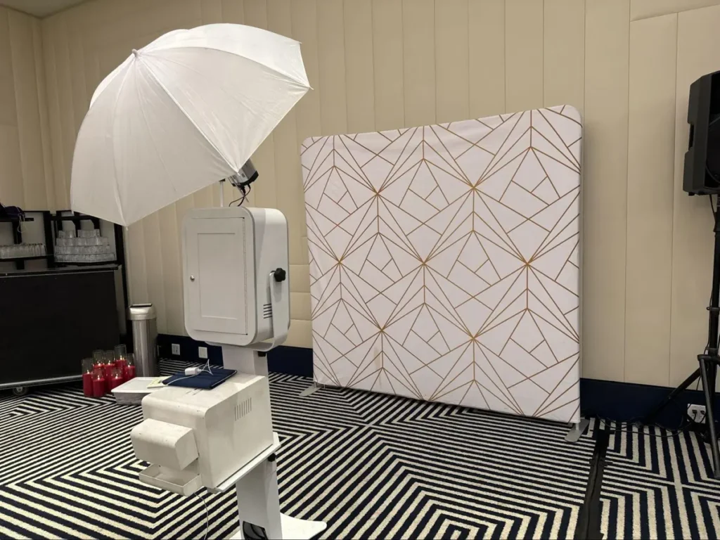 Professional photo booth setup with white umbrella lighting, geometric backdrop, and black and white floor pattern