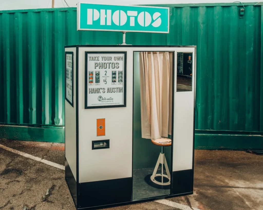 Retro-style photo booth by Hank's Austin offering 2 photos for $5 with a classic curtain entrance and green backdrop