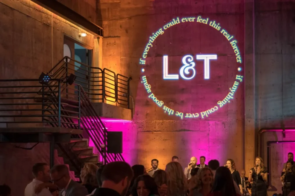 Stylish industrial venue with illuminated L&T logo projection and ambient lighting creating atmospheric event space