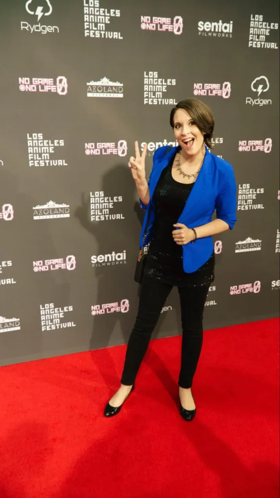 Woman in blue blazer posing at Los Angeles Anime Film Festival red carpet step-and-repeat backdrop featuring 'No Game No Life' branding