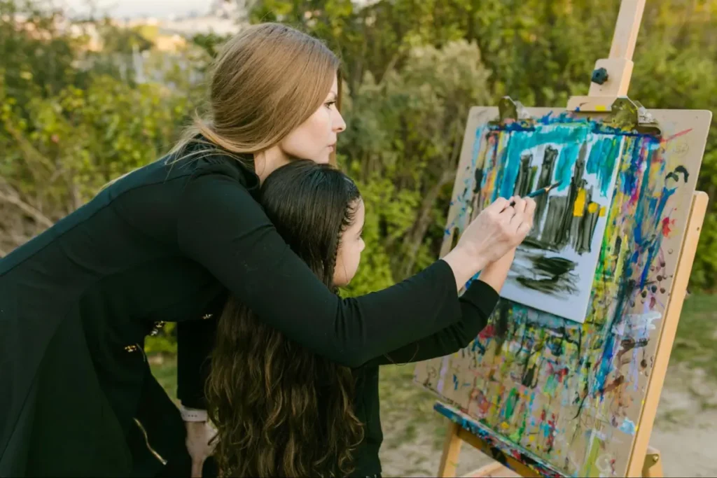 Adult and child painting together outdoors - Creative arts workshop event with collaborative painting opportunities in natural setting