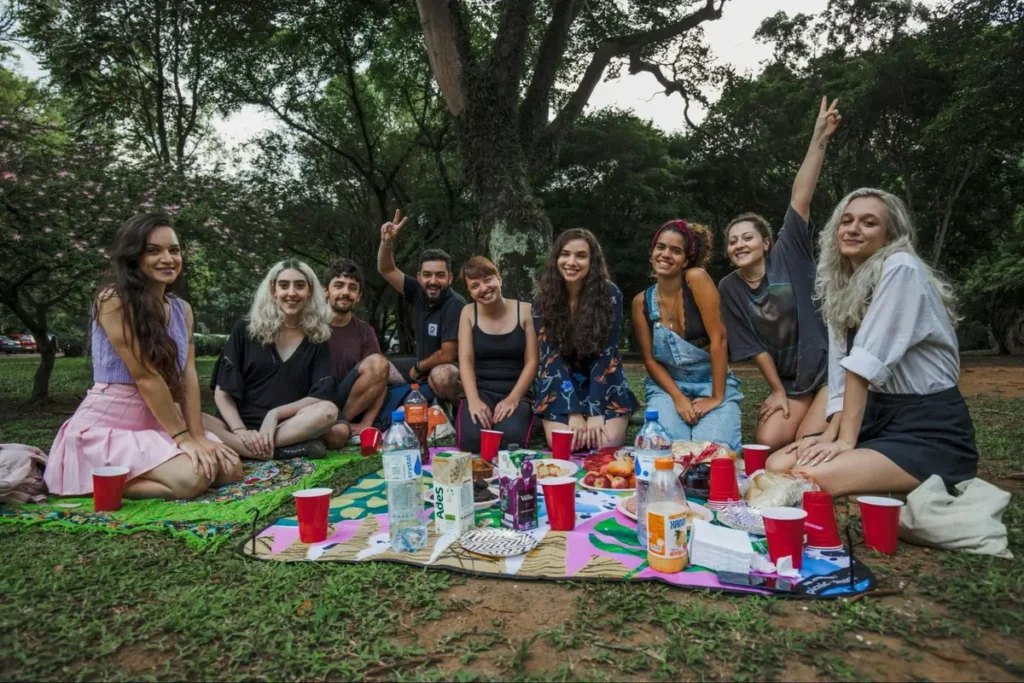 Friends enjoying outdoor picnic with colorful blankets and casual food spread, perfect for summer gathering themed events