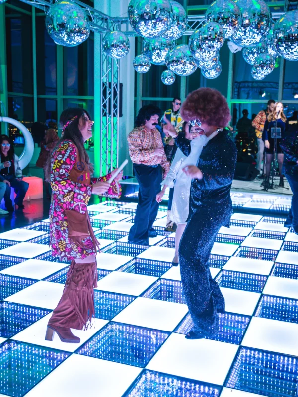 Guests dancing on an illuminated LED dance floor with disco theme